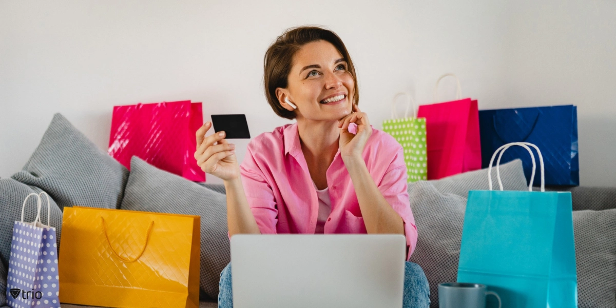 Woman online shopping and happy in front of laptop on sofa