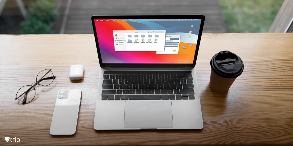 Top view of a MacBook laptop on a desk, accompanied by a smartphone and some accessories, an organized digital workspace.