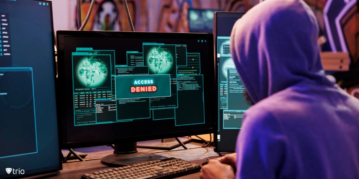 Frustrated hacker in a dark room, sitting in front of multiple screens with a red 'Access Denied' message, signifying an unsuccessful cyberattack.