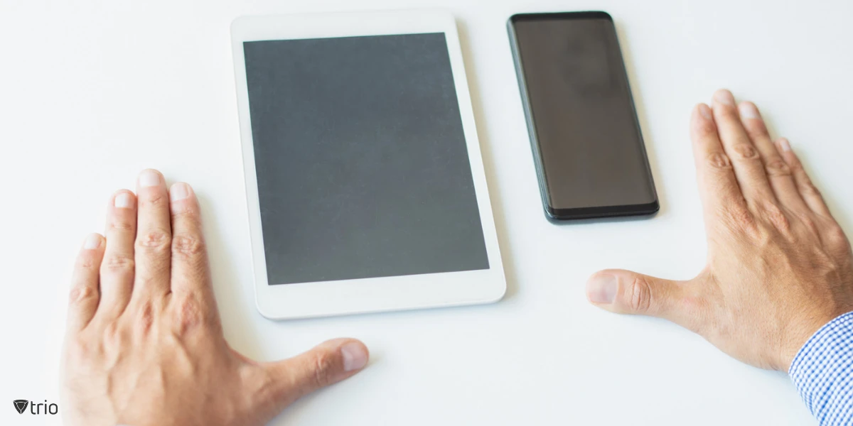 A close-up image of a businessman using both a smartphone and a tablet, showing the increasing trend of individuals owning multiple digital devices, highlighting the logic behind businesses adopting BYOD.