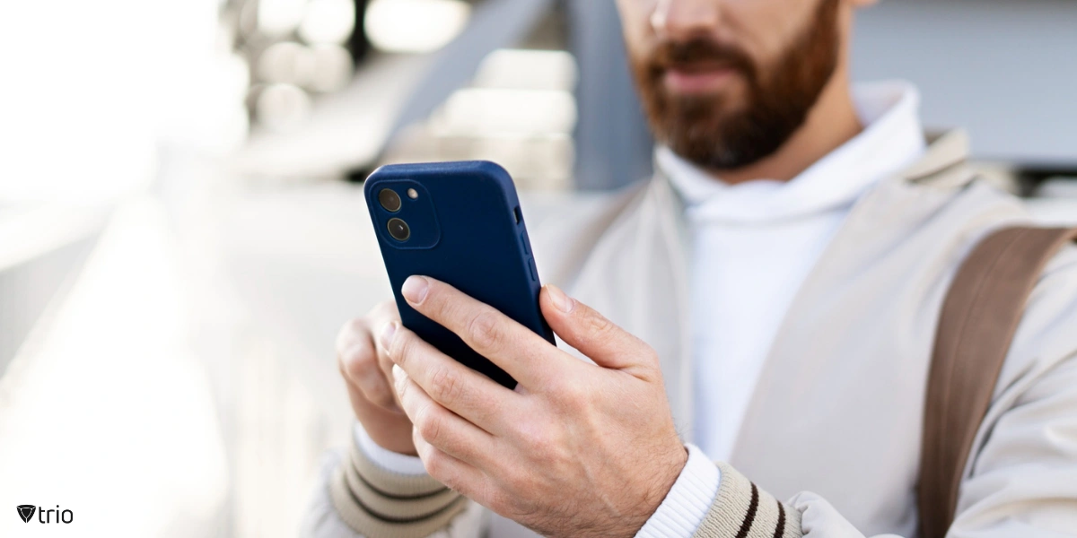 Close-up image of a man holding a smartphone in both hands, focused on the device’s screen.