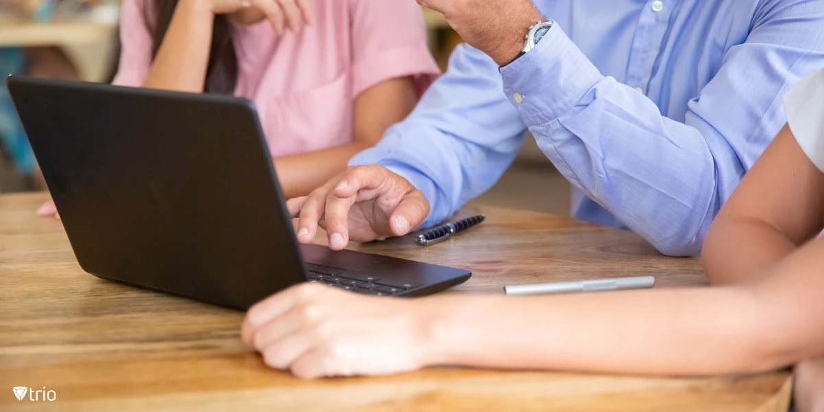 Business team meeting around a table with an open laptop, discussing and sharing ideas, as they engage in a review and validation process.