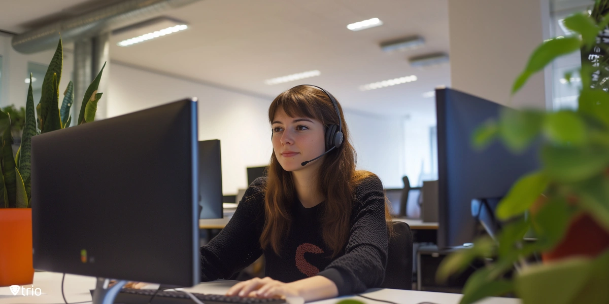 Die Managerin wird fotografiert, wie sie lächelnd nach vorne blickt und an einem Computer sitzt