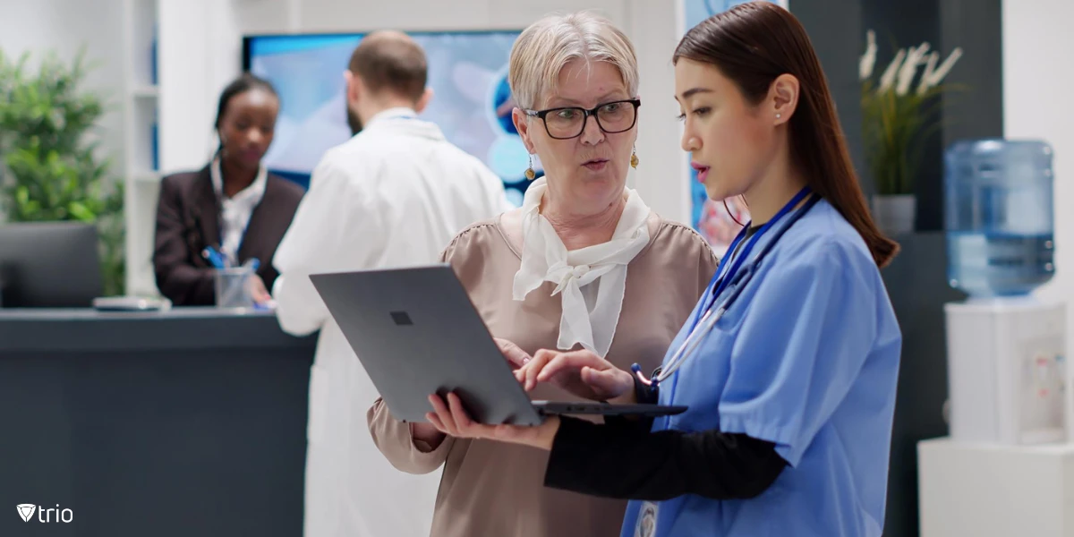 Senior woman and medical assistant using a laptop, doing consultation in hospital reception