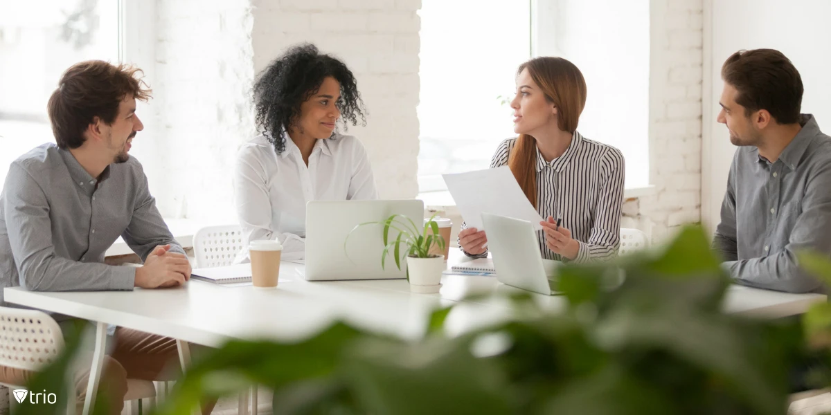 [Implementierungsprozess] [Ein vierköpfiges Team diskutiert in einem White Office, wie Cybersicherheits-Frameworks implementiert werden können.] 