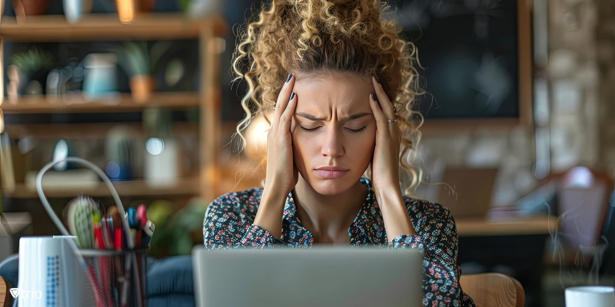 overwhelmed woman with hands in her hair sitting in front of a laptop