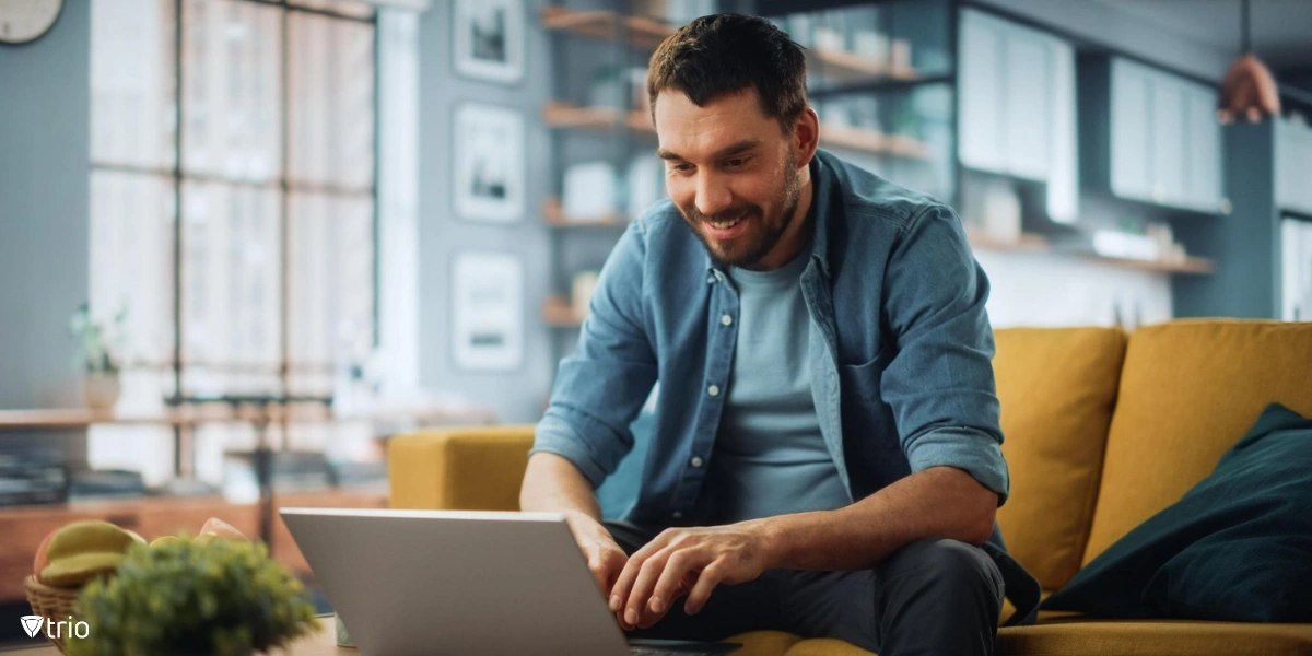 A man sitting on a sofa, using a laptop.