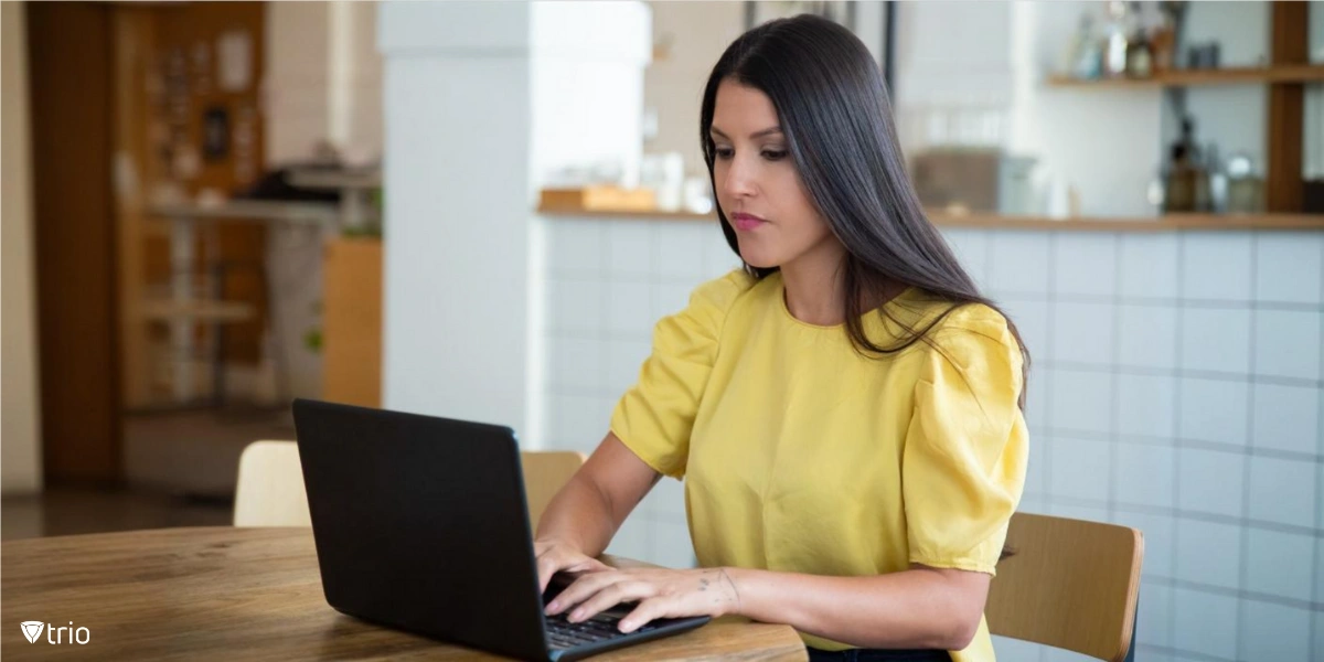 A woman sitting at a table, using a laptop.