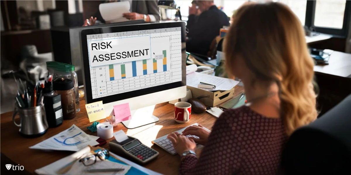 woman working on a messy desk in an office with risk assessment chart on her computer