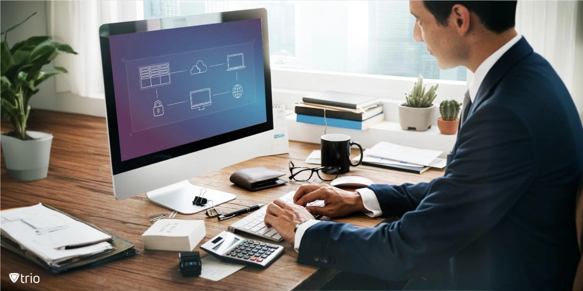 A professional working at a desktop computer with a schematic of a cloud computing setup displayed on the screen. It illustrates the components of a secure and interconnected virtual workspace