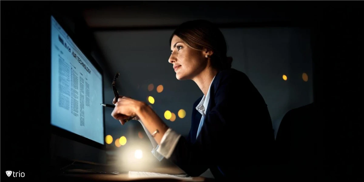 Businesswoman focused on the text on her computer screen with her glasses and pen in her hand