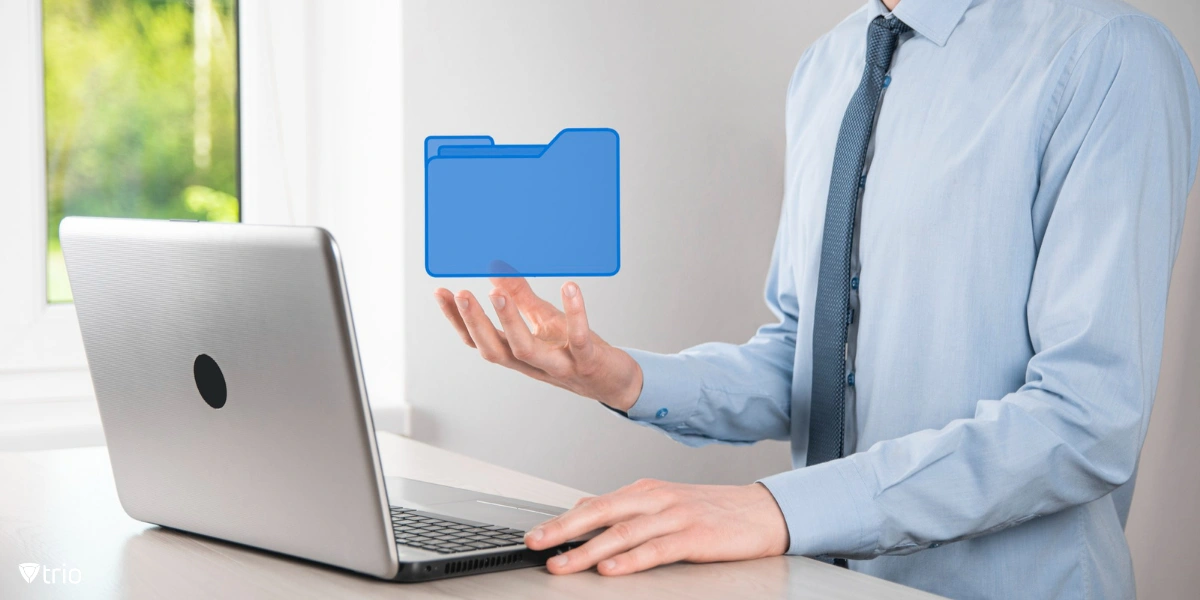 Businessman holding folder icon while sitting in front of laptop