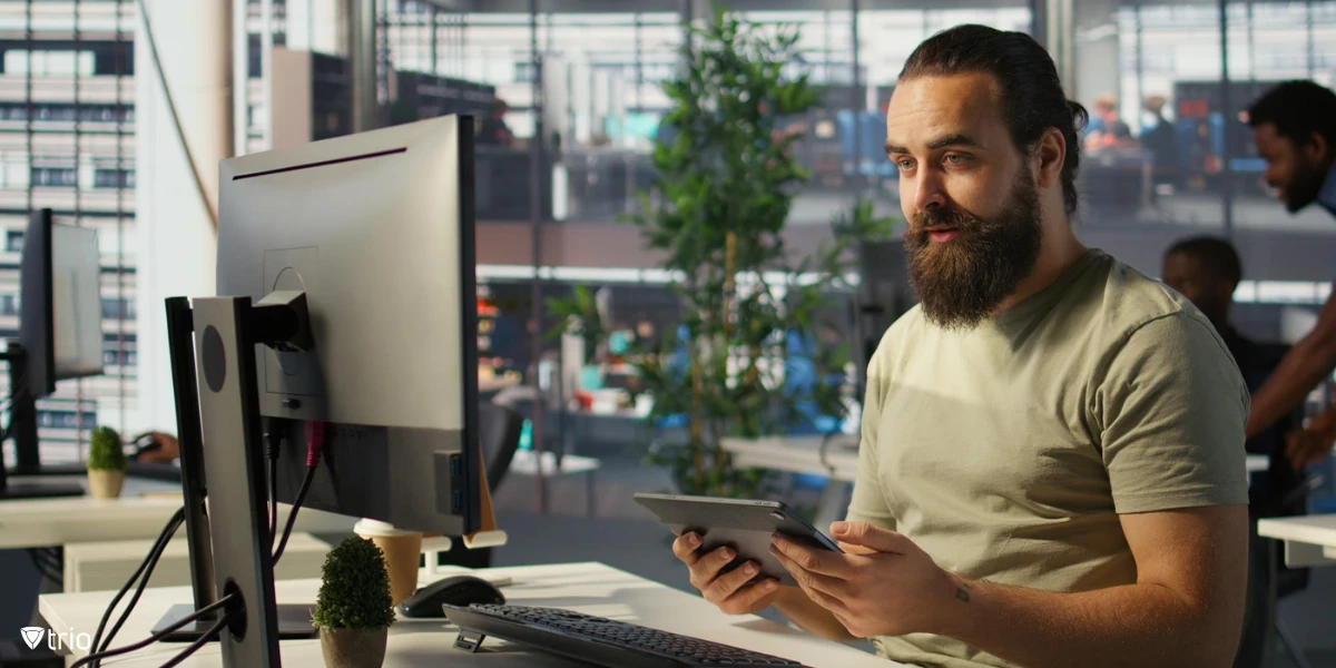 Coworkers collaborating one showing notes while other is in front of computer