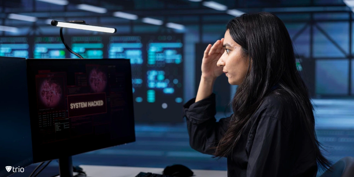 panicked woman sitting in front of computer with “system hacked” message showing