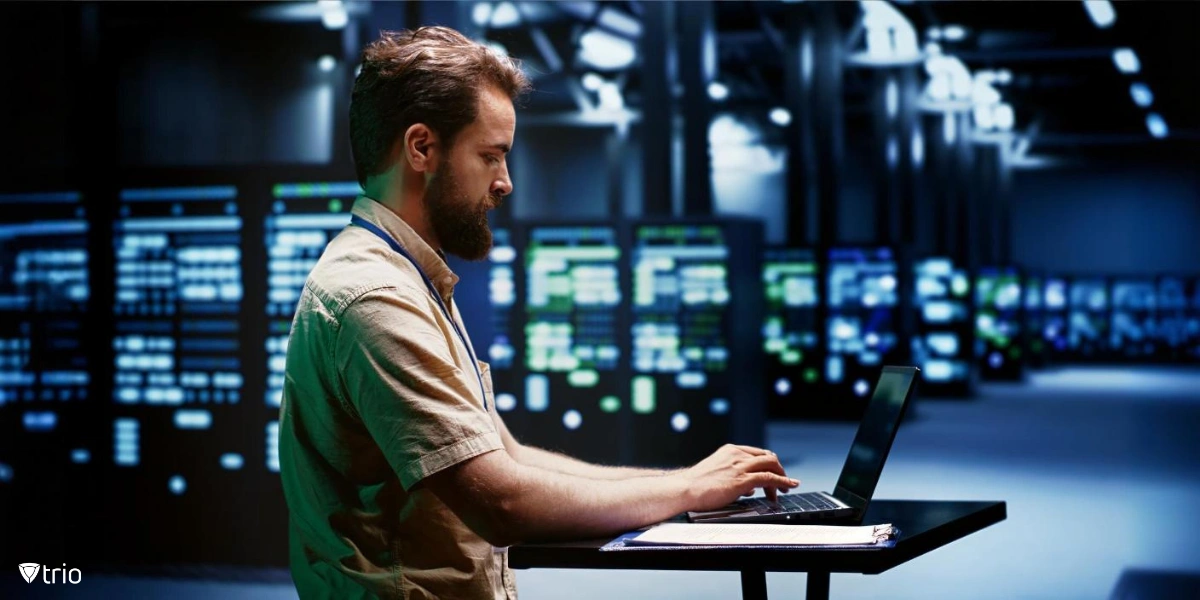 man working on a laptop at a standing desk in the server room