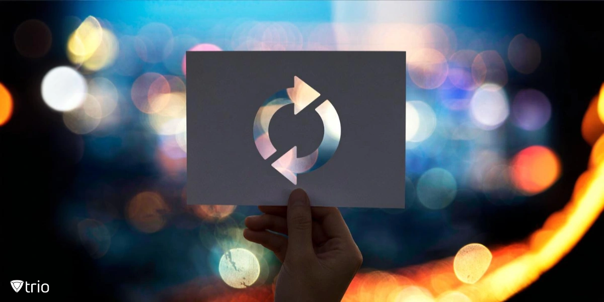 A hand holds a perforated paper showing a refresh or update icon, set against a colorful, blurred city lights background