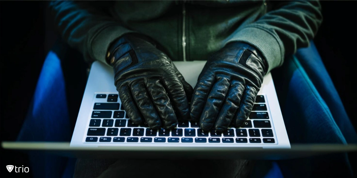 A person wearing black gloves typing on a laptop